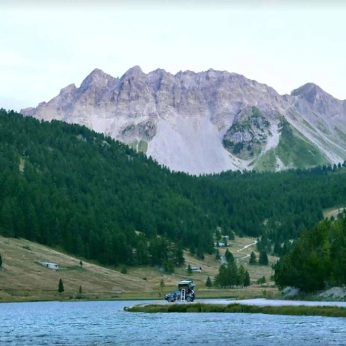 Paysage montagneux pittoresque avec une végétation luxuriante et un lac serein, idéal pour des aventures en plein air et du camping.
