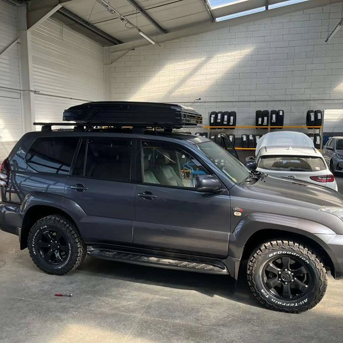 SUV garé dans un garage avec une tente rigide sur le toit pour 2-3 personnes, prête pour des aventures de camping.